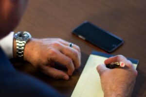 person writing notes on white ruled paper