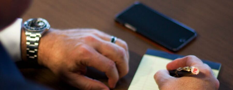 person writing notes on white ruled paper